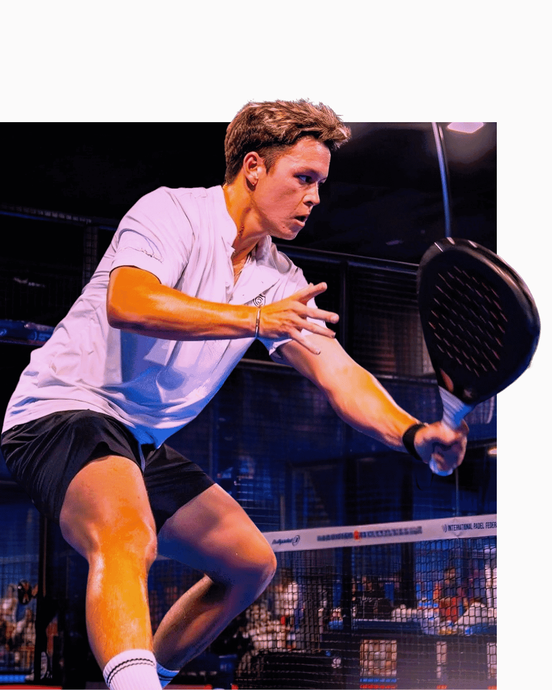 A padel player preparing a shot on a purple-lit court at night